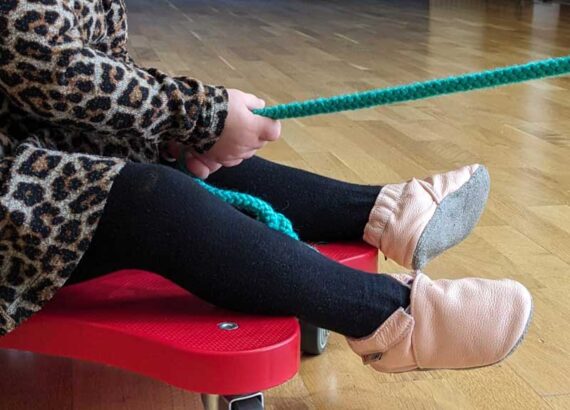 Kind wird auf einem Rollbrett gezogen